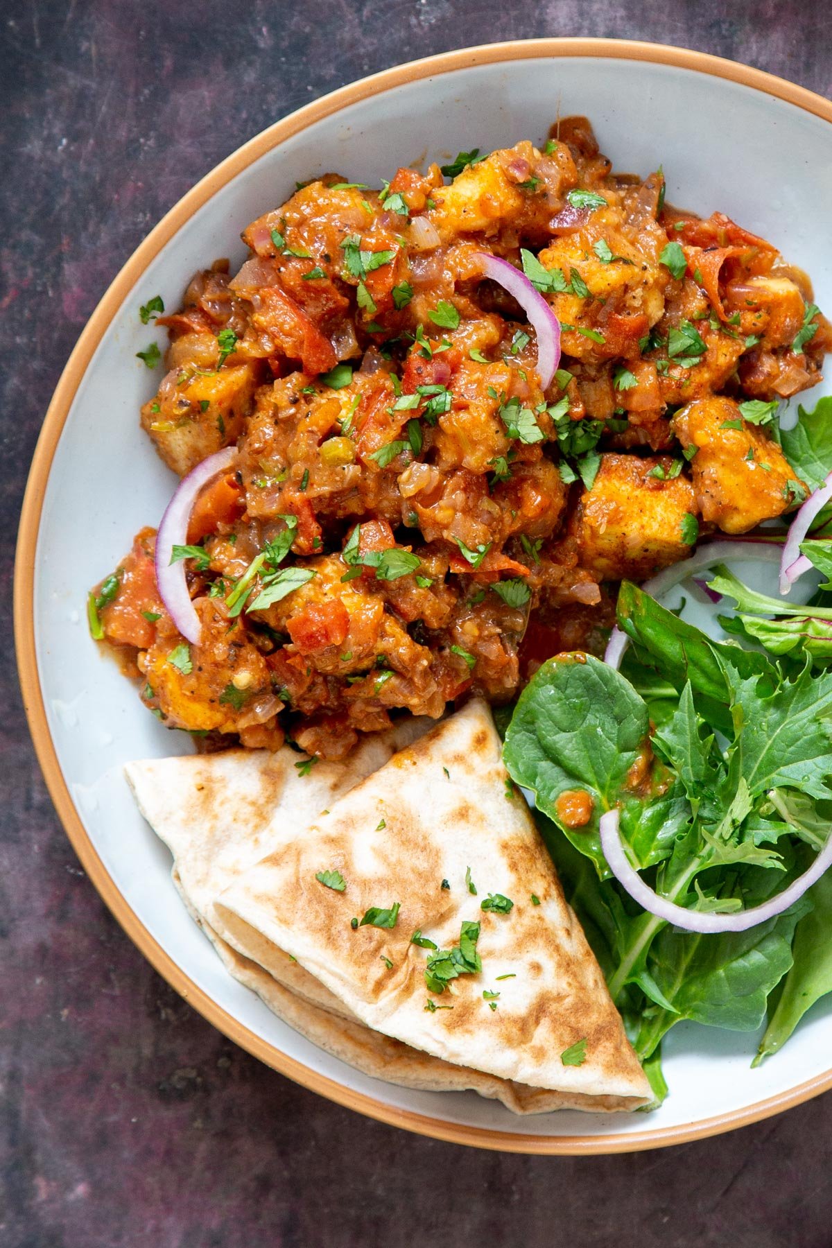 a serving of vegan khada masala murg curry with tofu served with a side of spinach and flatbread
