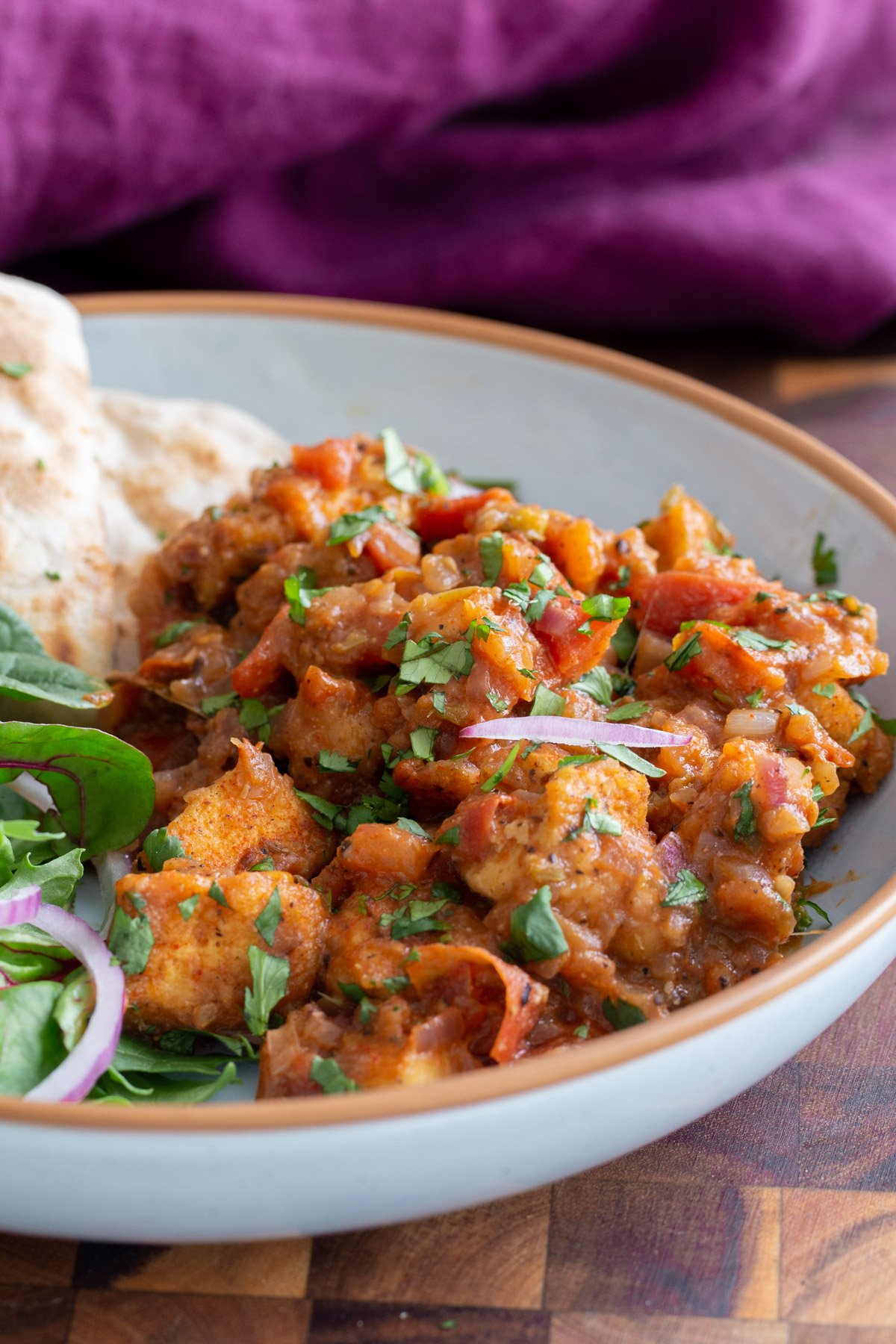 a serving of Khada Masala Murg with flatbread and a side salad