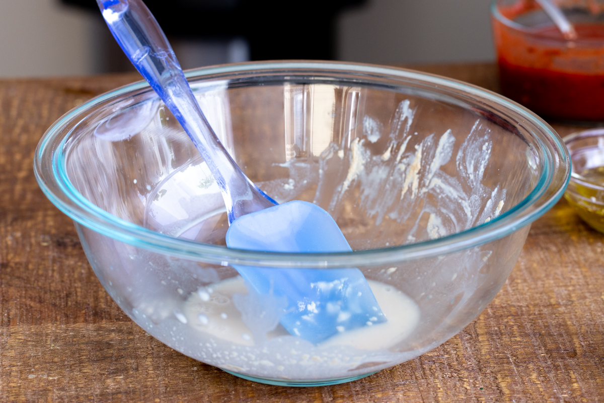 dry yeast being activated in a bowl with warm water