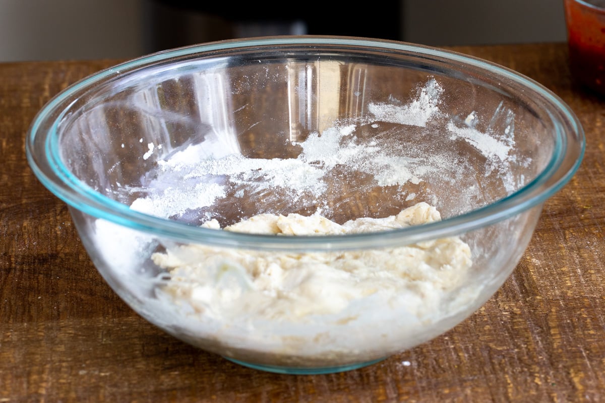 vegan pizza dough proofing in a glass bowl