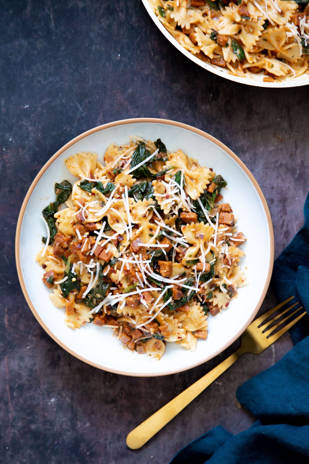 a plate of vegan pepperoni pasta with a golden fork on the side