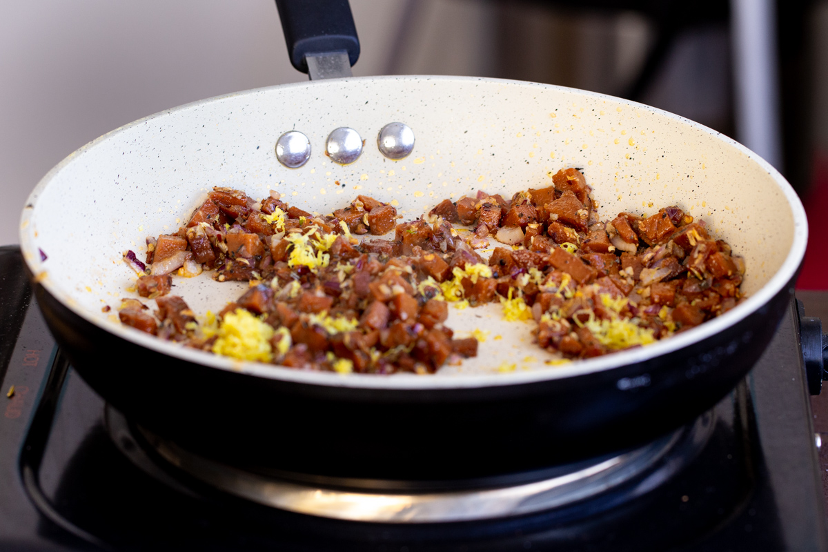 fresh lemon zest and vegan sausage frying in a pan to make pasta sauce