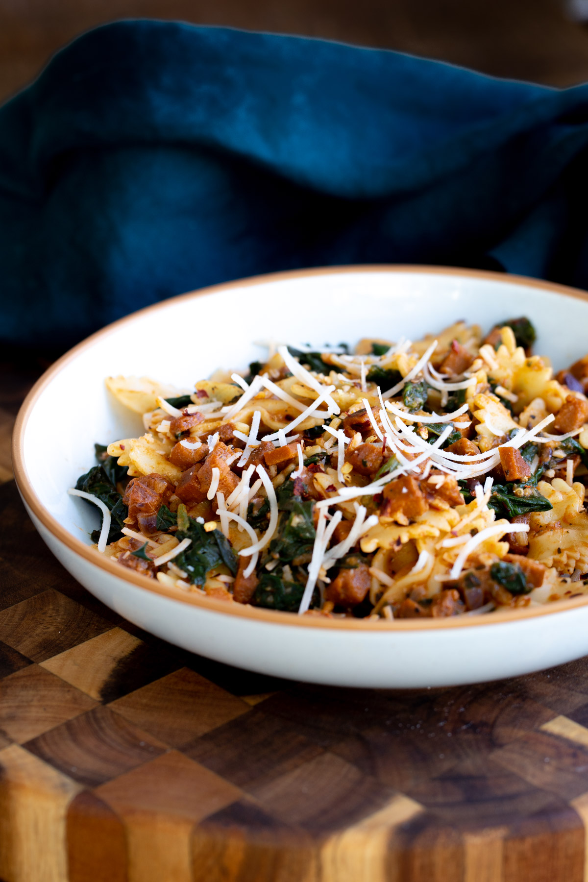 side view of a bowl of vegan pepperoni pasta sprinkled with vegan parmesan cheese