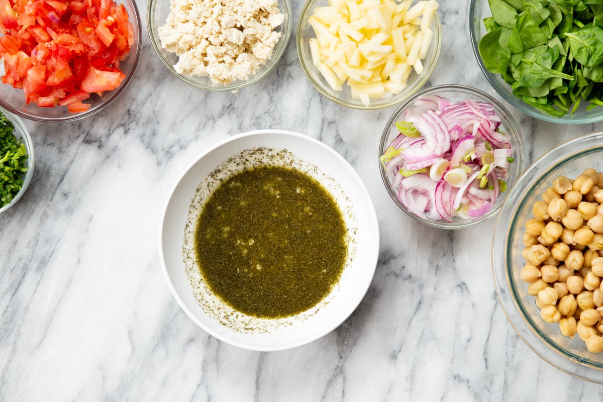 lemon dill dressing in a small white dish surrounded by salad ingredients