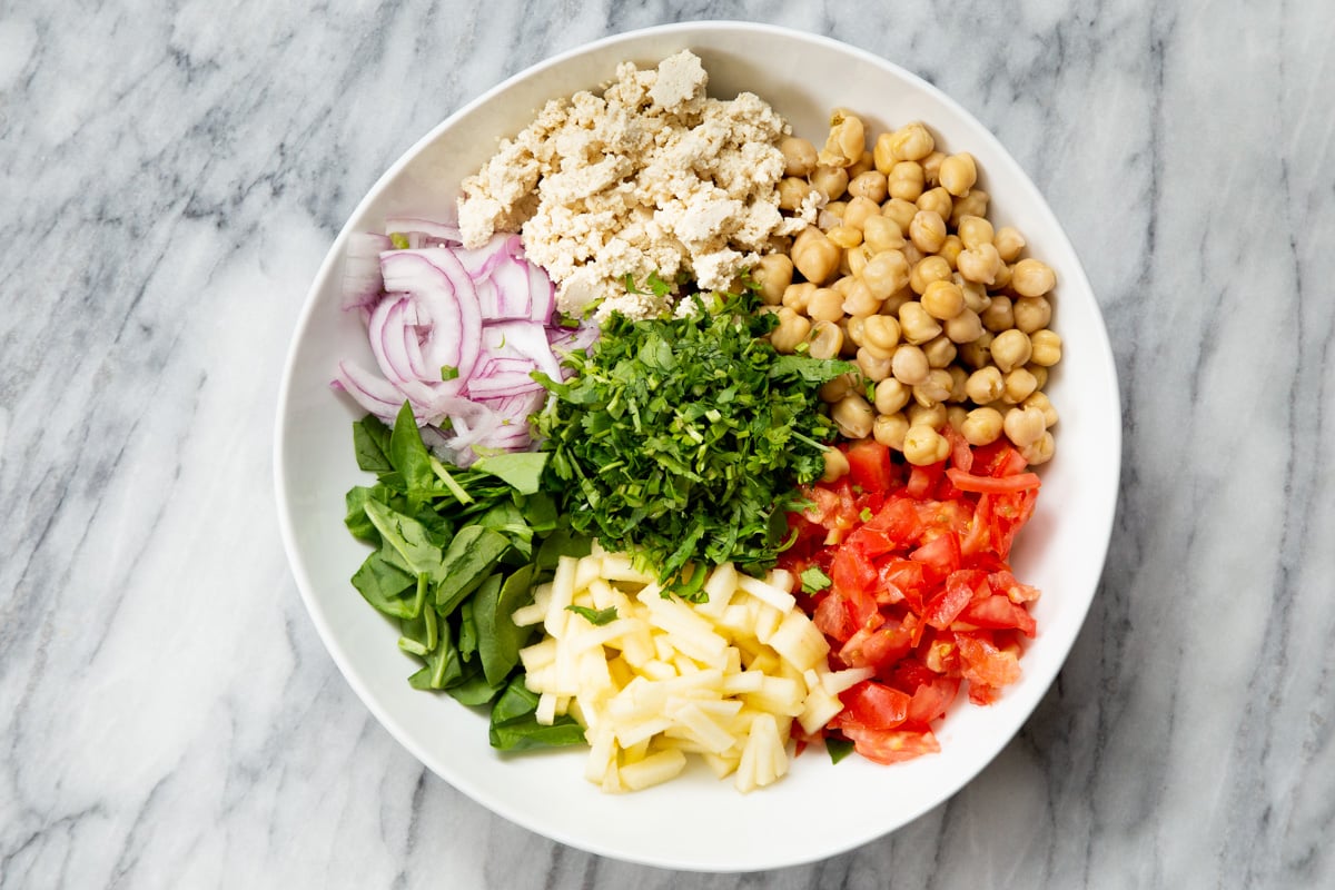 a white bowl with assembled chickpea salad ingredients