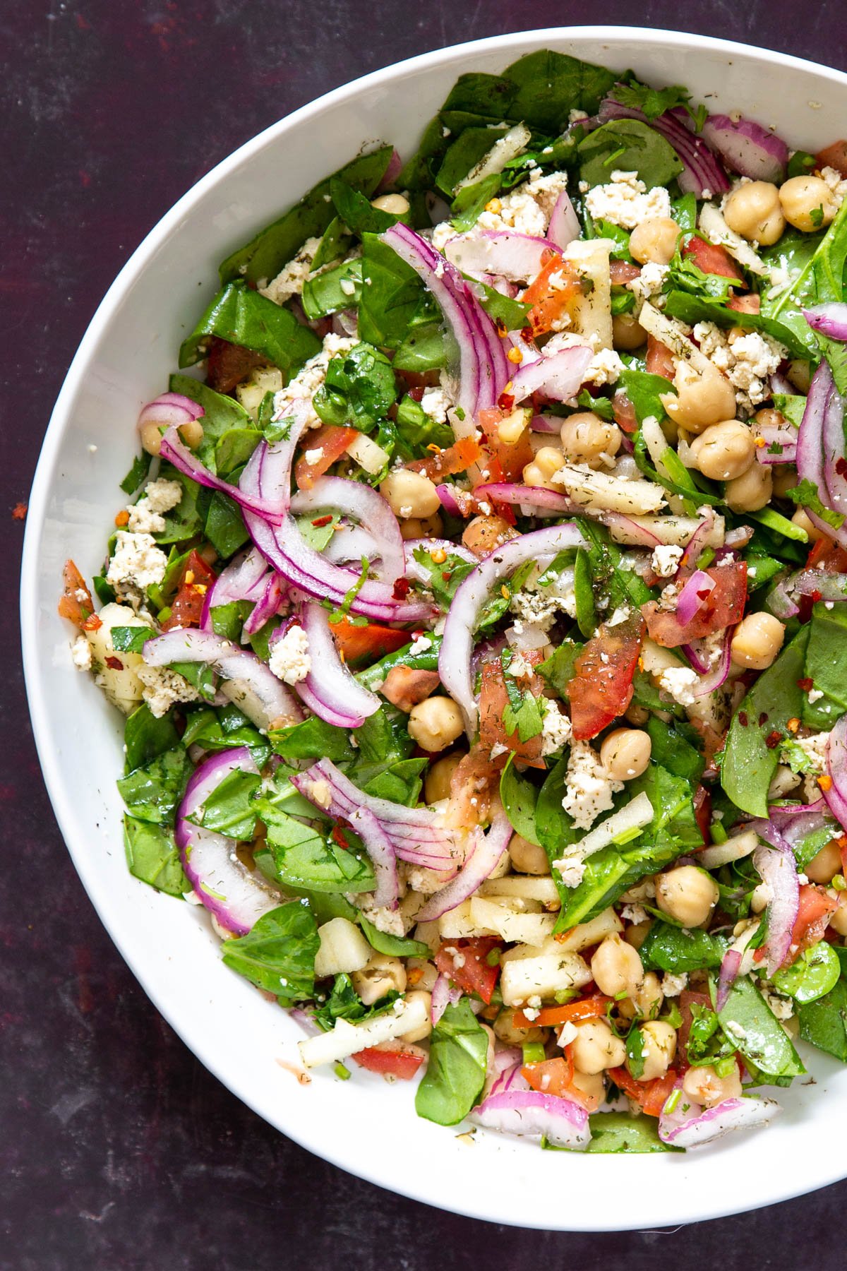 a white platter with vegan chickpea salad with onion, tomatoes and crumbled tofu