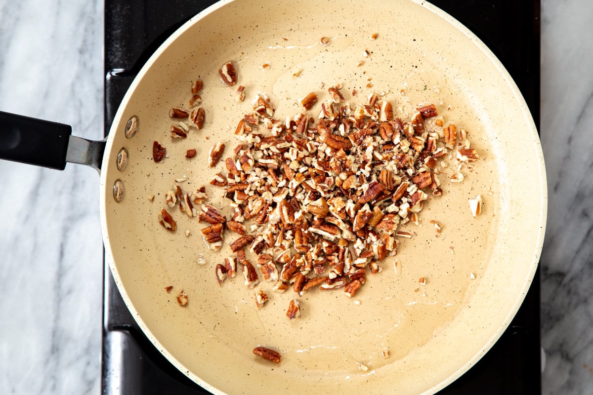 chopped pecans being toasted in a pan.
