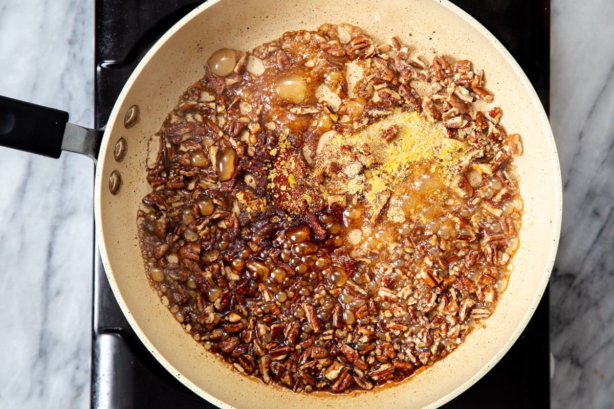 toasted pecans caramelizing in a mix of maple syrup soy sauce and spices