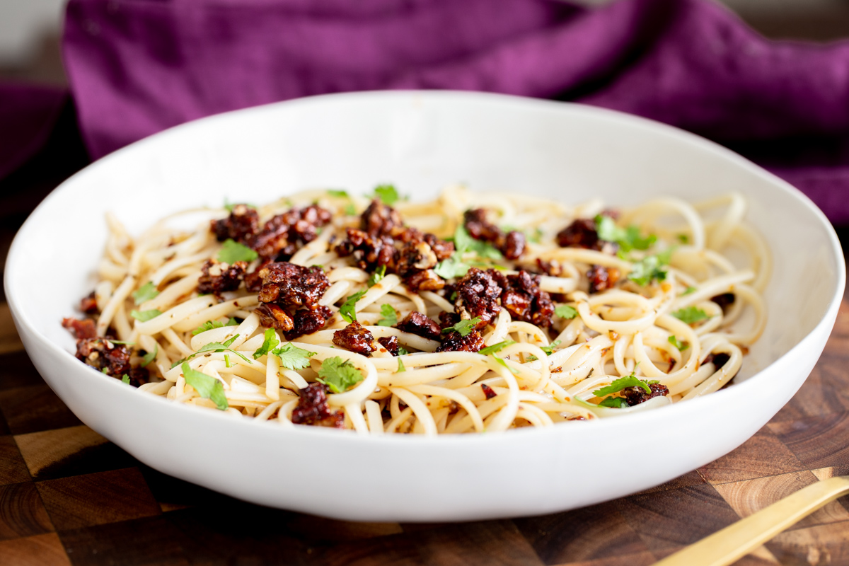 vegan pasta with chili garlic oil topped with candied pecans