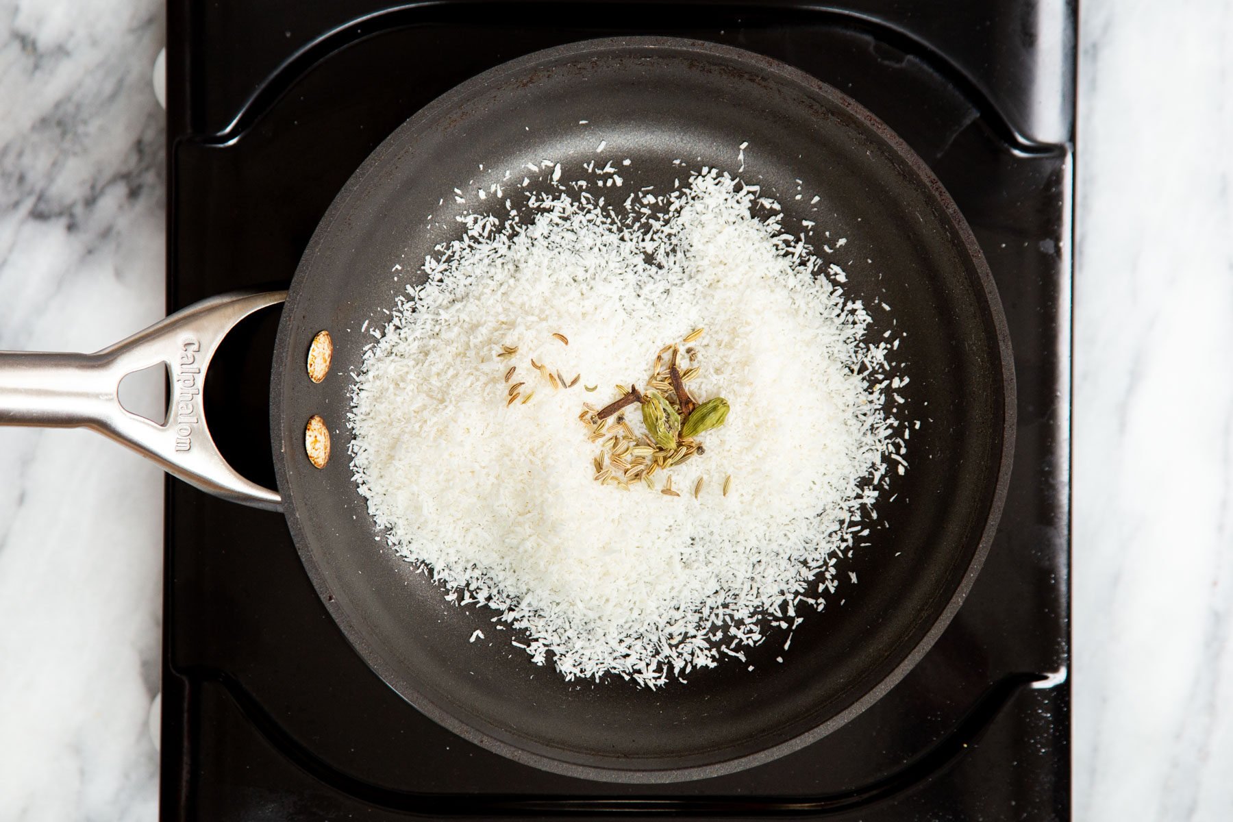 coconut being toasted in a black sauteeing pan