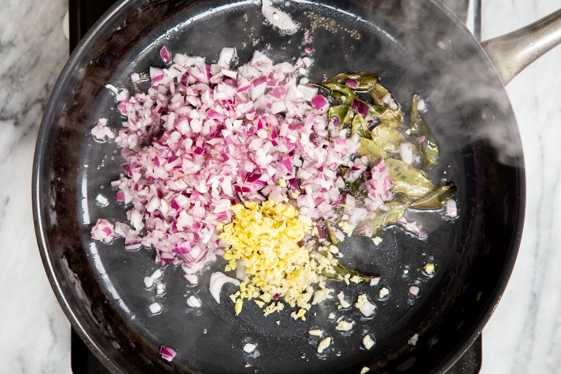mustard seeds, onion, curry leaves and ginger in a frying pan
