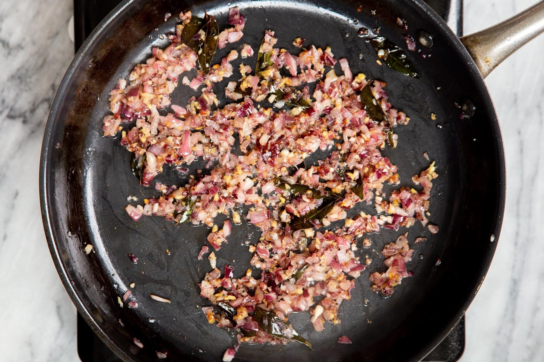 fried onion and ginger with tempering in a frying pan 
