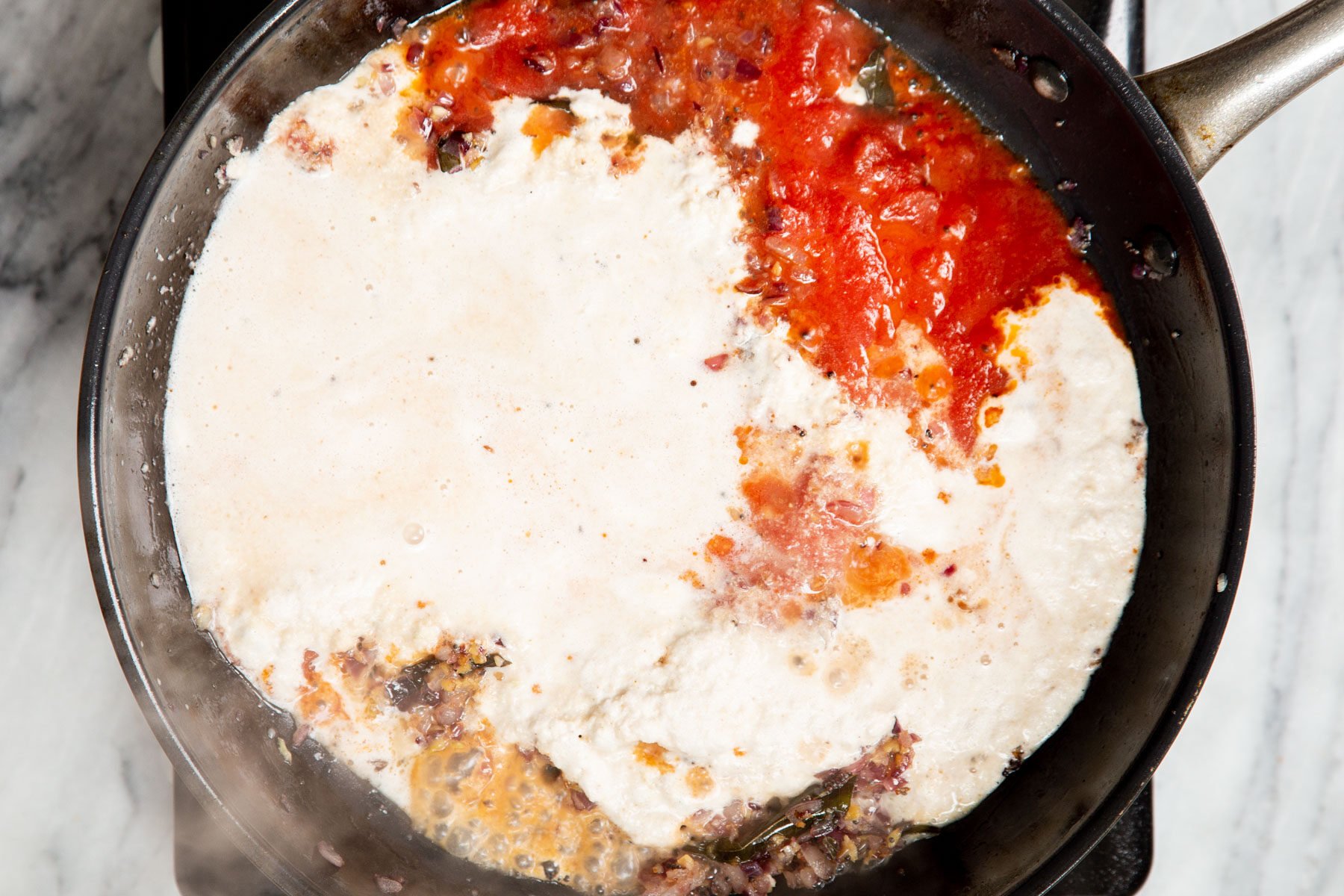 tomato sauce and coconut paste simmering in a pan to form malabar curry gravy