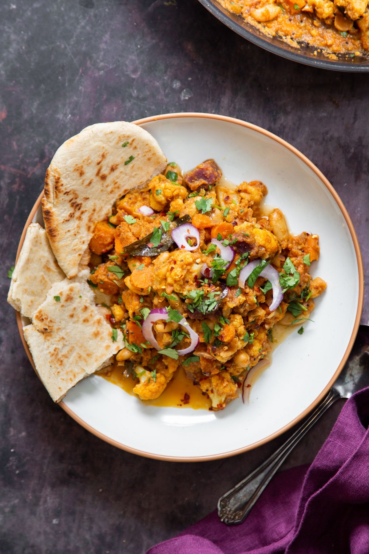 vegan malabar curry served with naan bread in a white plate