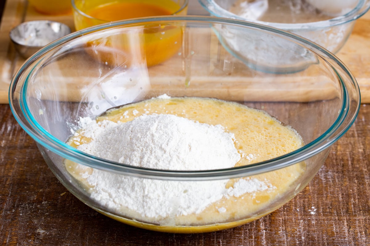 dry and wet ingredients being combined in a glass bowl to make cake batter