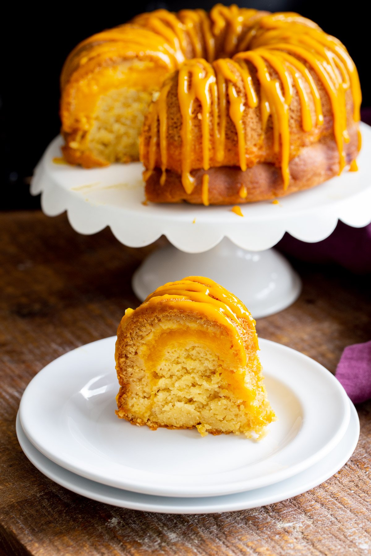 a slice of vegan mango bundt cake with a cake stand in the background