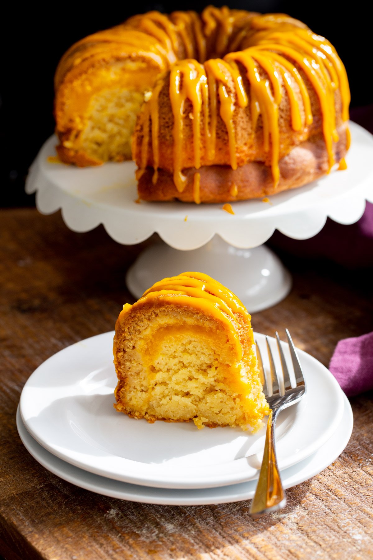 a slice of vegan fresh mango bundt cake with mango swirl and mango drizzle