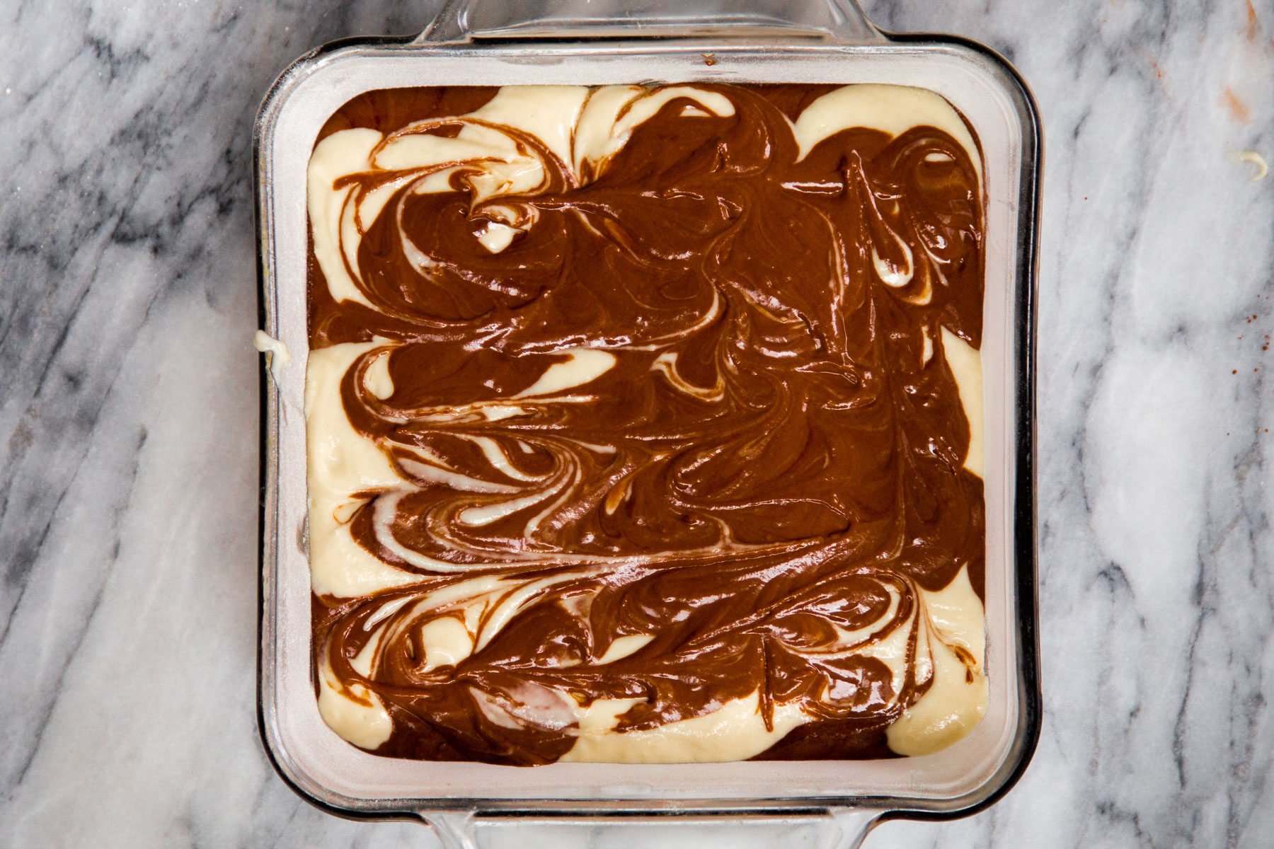 swirled vegan marble cake batter in a square cake pan