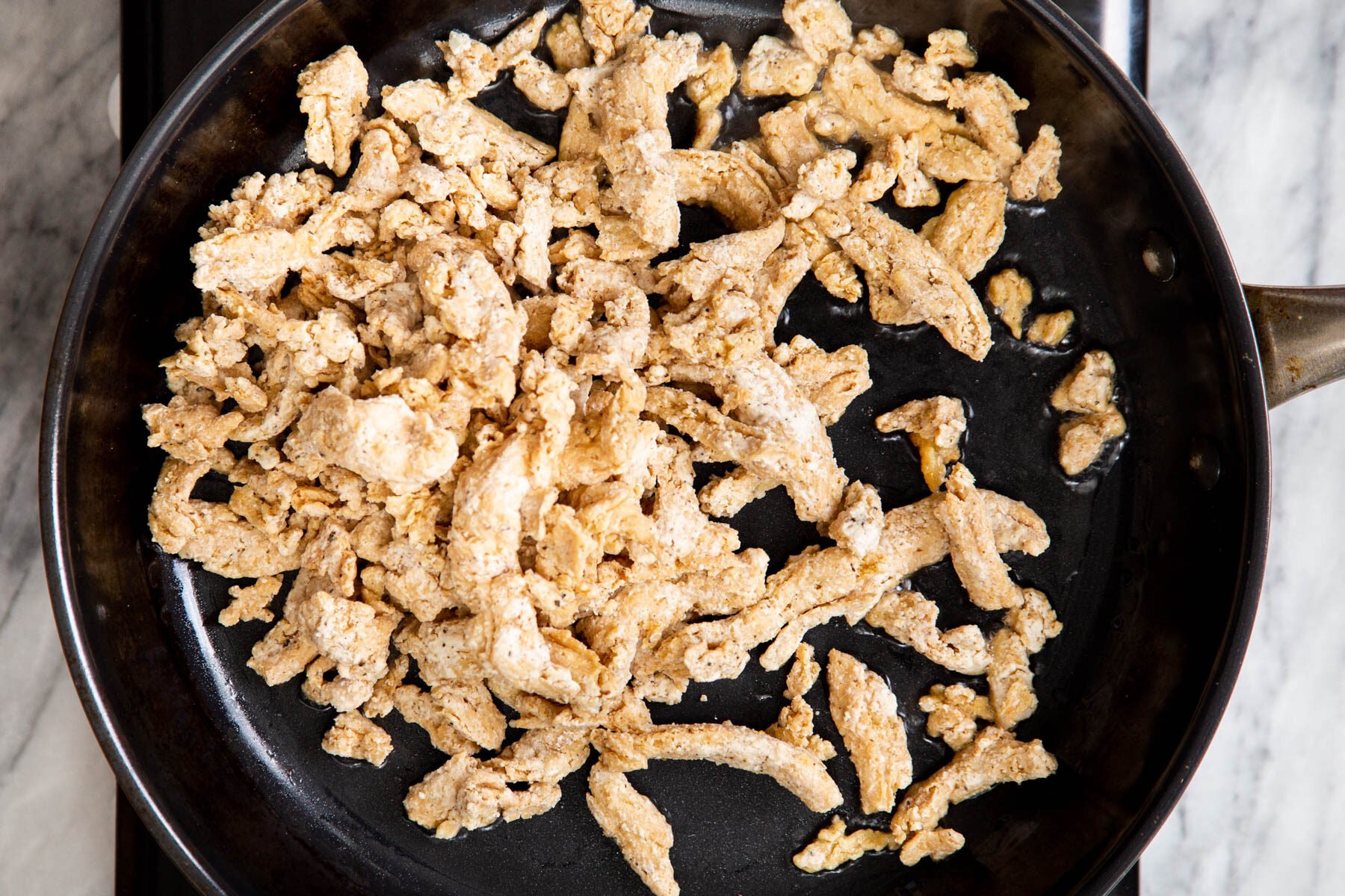 soy chunks being fried in a black skillet