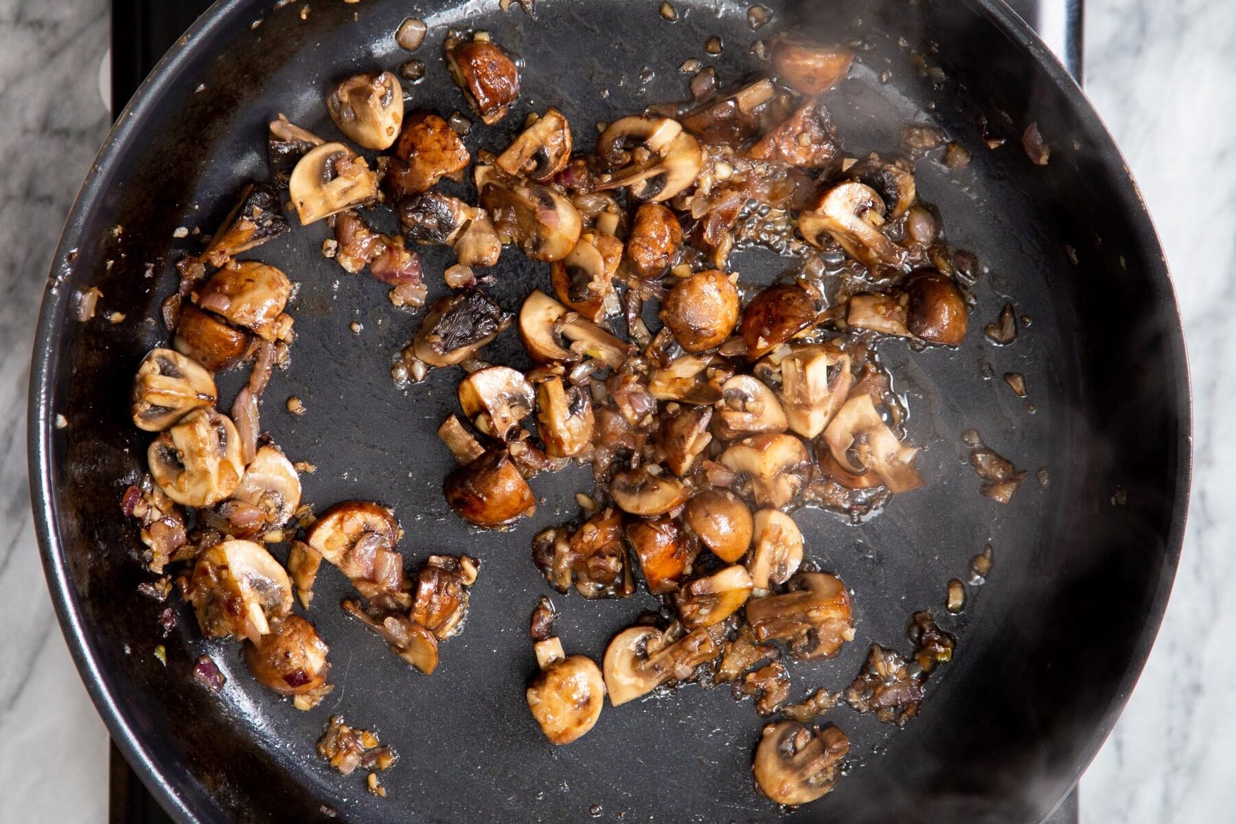 golden fried muhsrooms with garlic and onion in a skillet