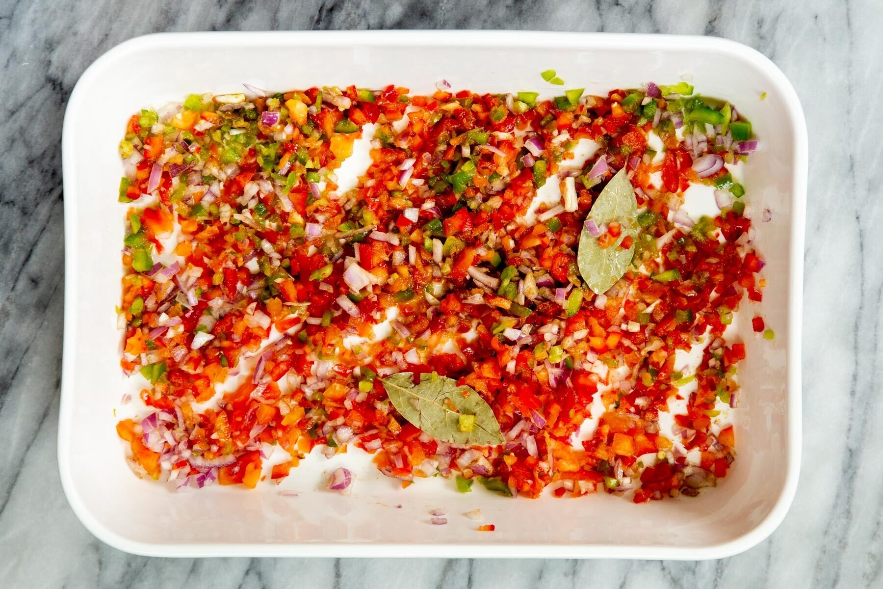 sauteed chopped onion and bell pepper in a white casserole dish