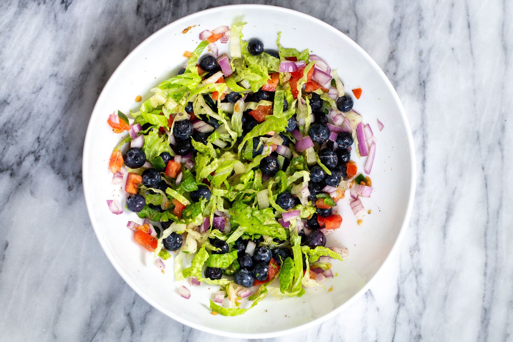 blueberry tomato salad in a white bowl