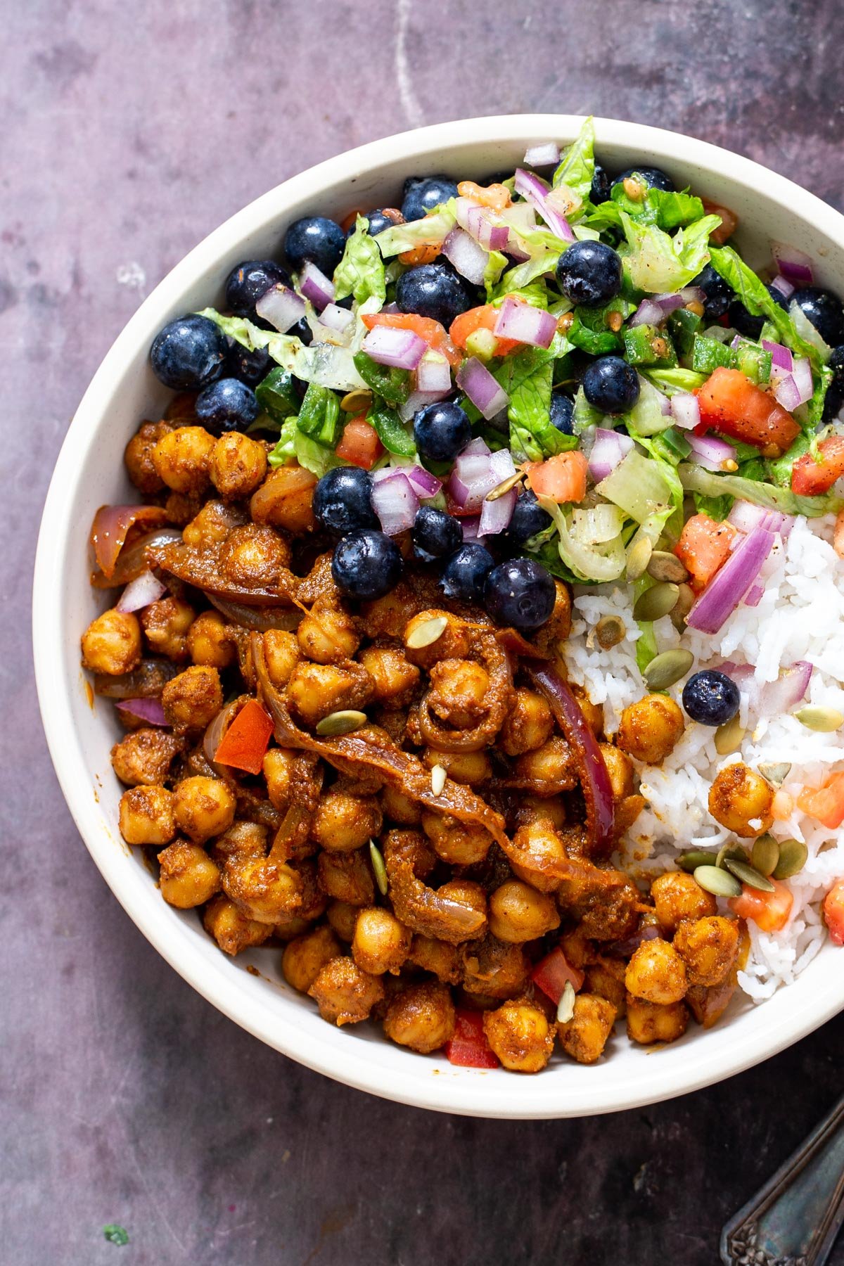 a bowl with rice, berbere spiced chickpeas and blueberry tomato salad