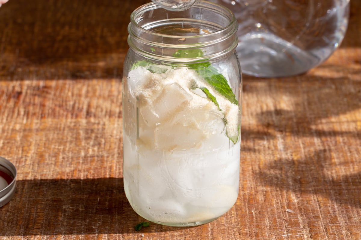 ice cubes, lemon juice and mint leaves in a mason jar