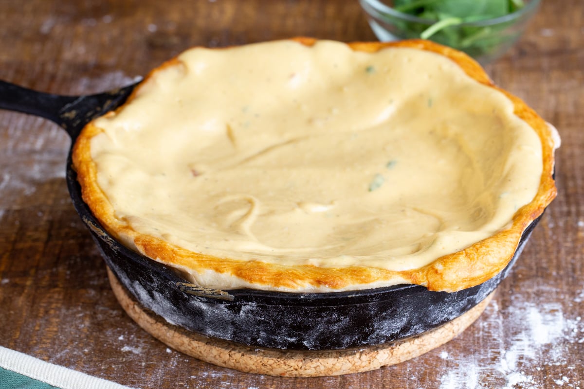 vegan cheese sauce being added to prebaked pretzel pizza crust