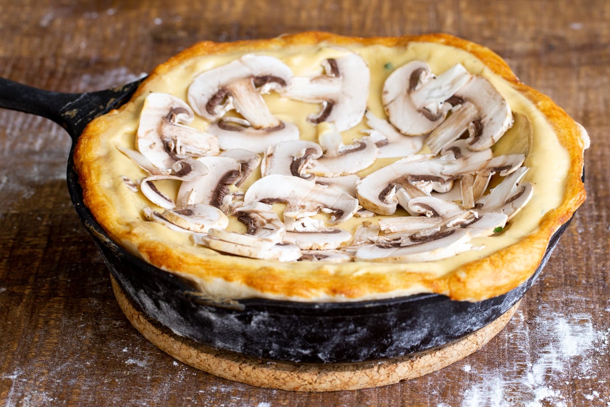 a prebaked vegan deep dish pizza topped with cheese sauce and sliced mushrooms
