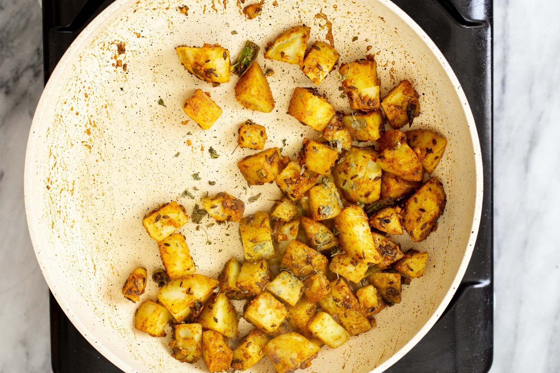 jeera potatoes cooking in a pan with spices
