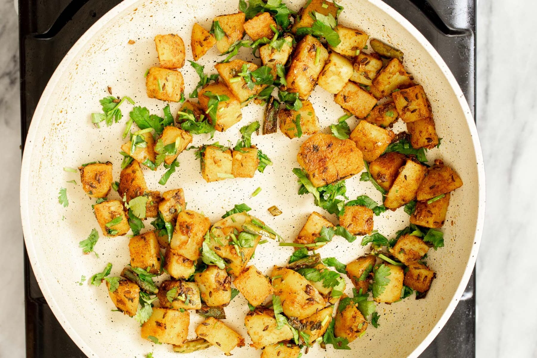 fresh chopped cilantro being sprinkled over potatoes