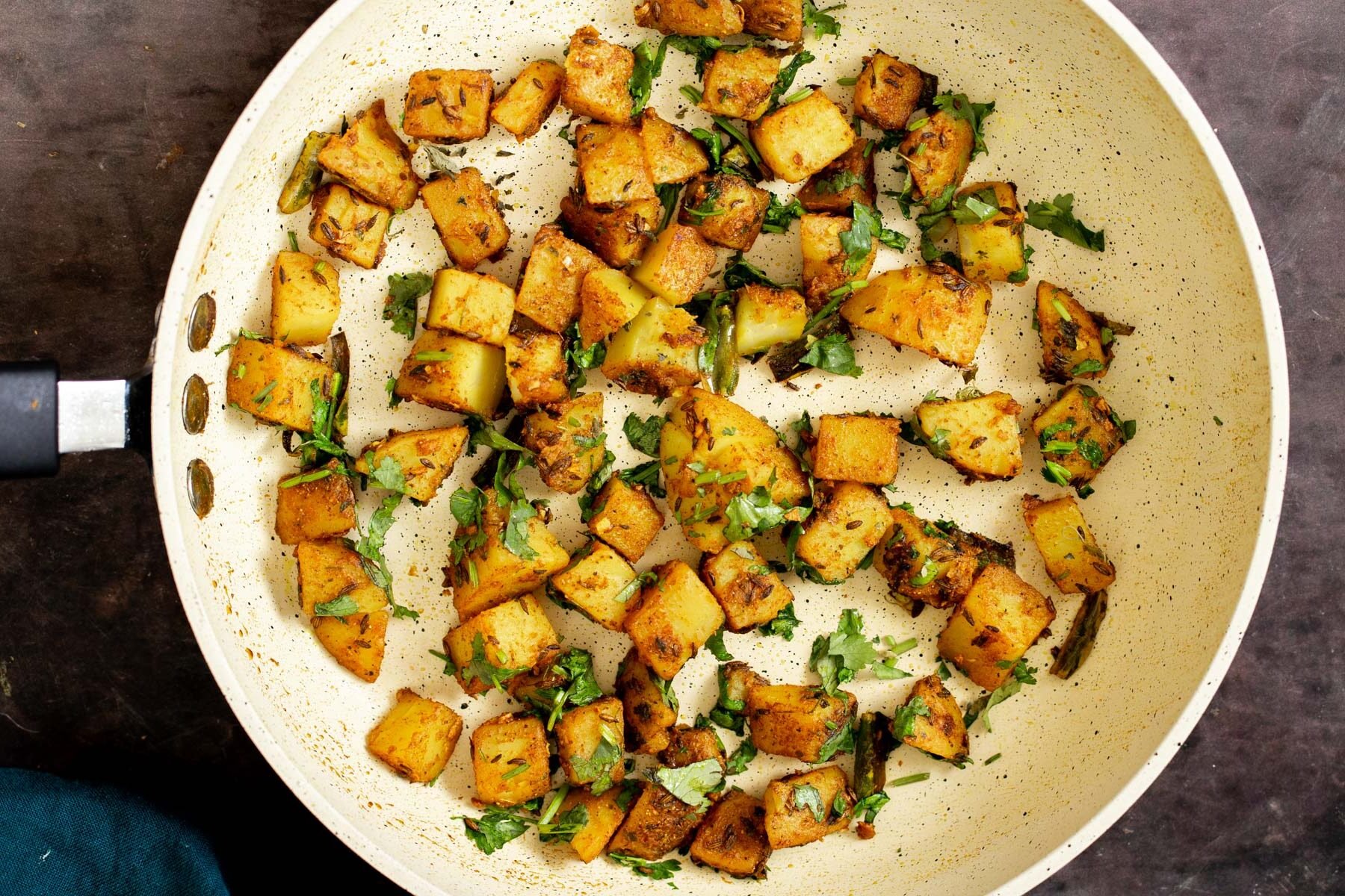 Indian spiced cumin potatoes in a white frying pan