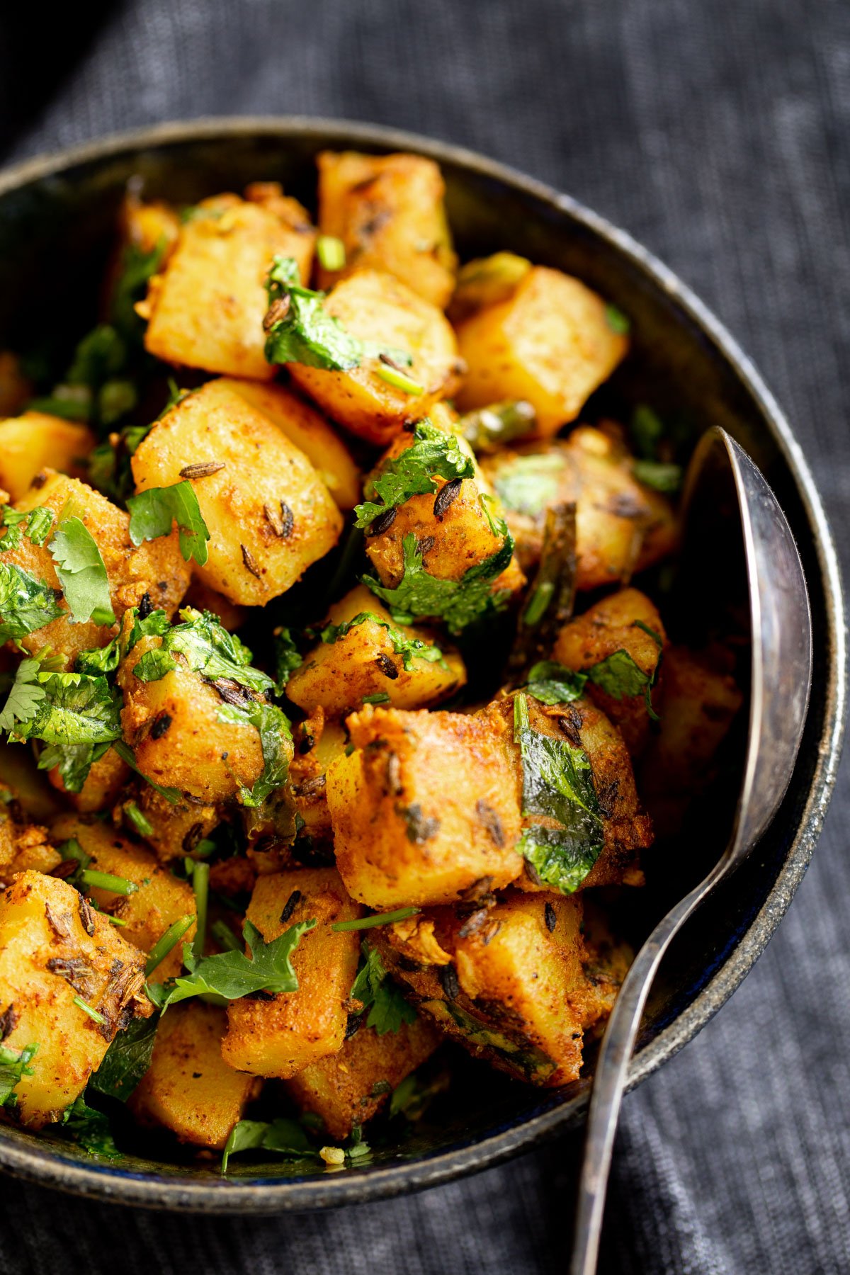 a bowl with cumin spiced jeera aloo potatoes sprinkled with fresh coriander