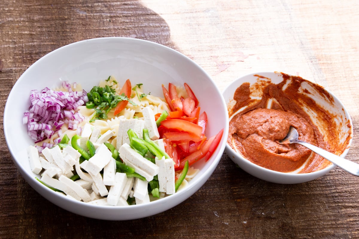 pasta salad ingredients next to a small bowl with tikka masala dressing