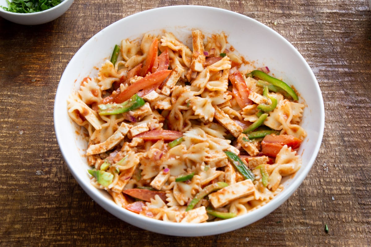tossed vegan Tikka Masala Pasta Salad in a white salad bowl