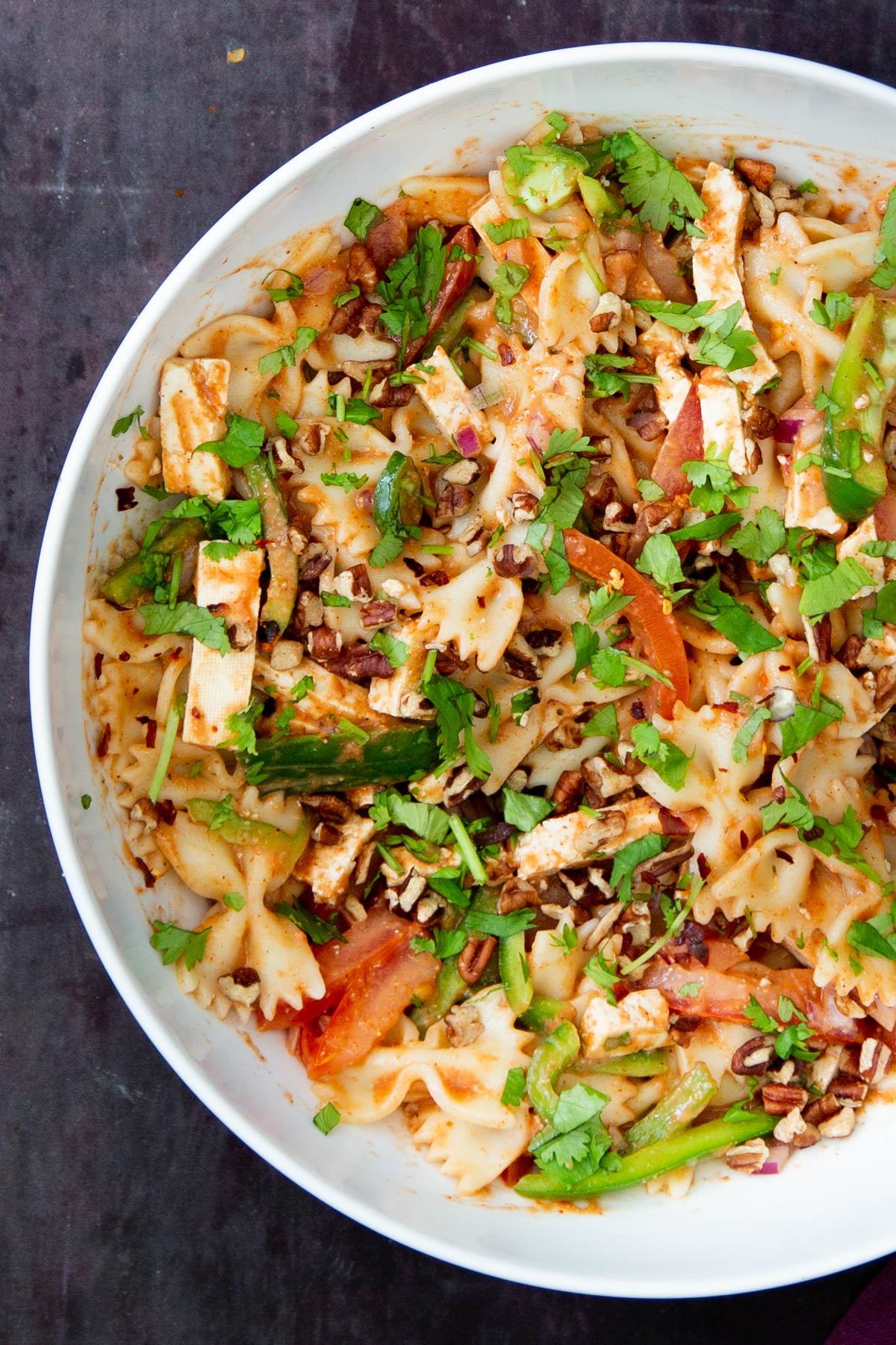 a white bowl with vegan tikka masala pasta salad sprinkled with chopped herbs