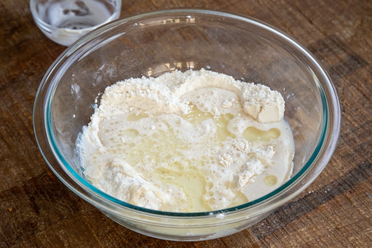 wet ingredients being added to dry ingredients in a glass bowl