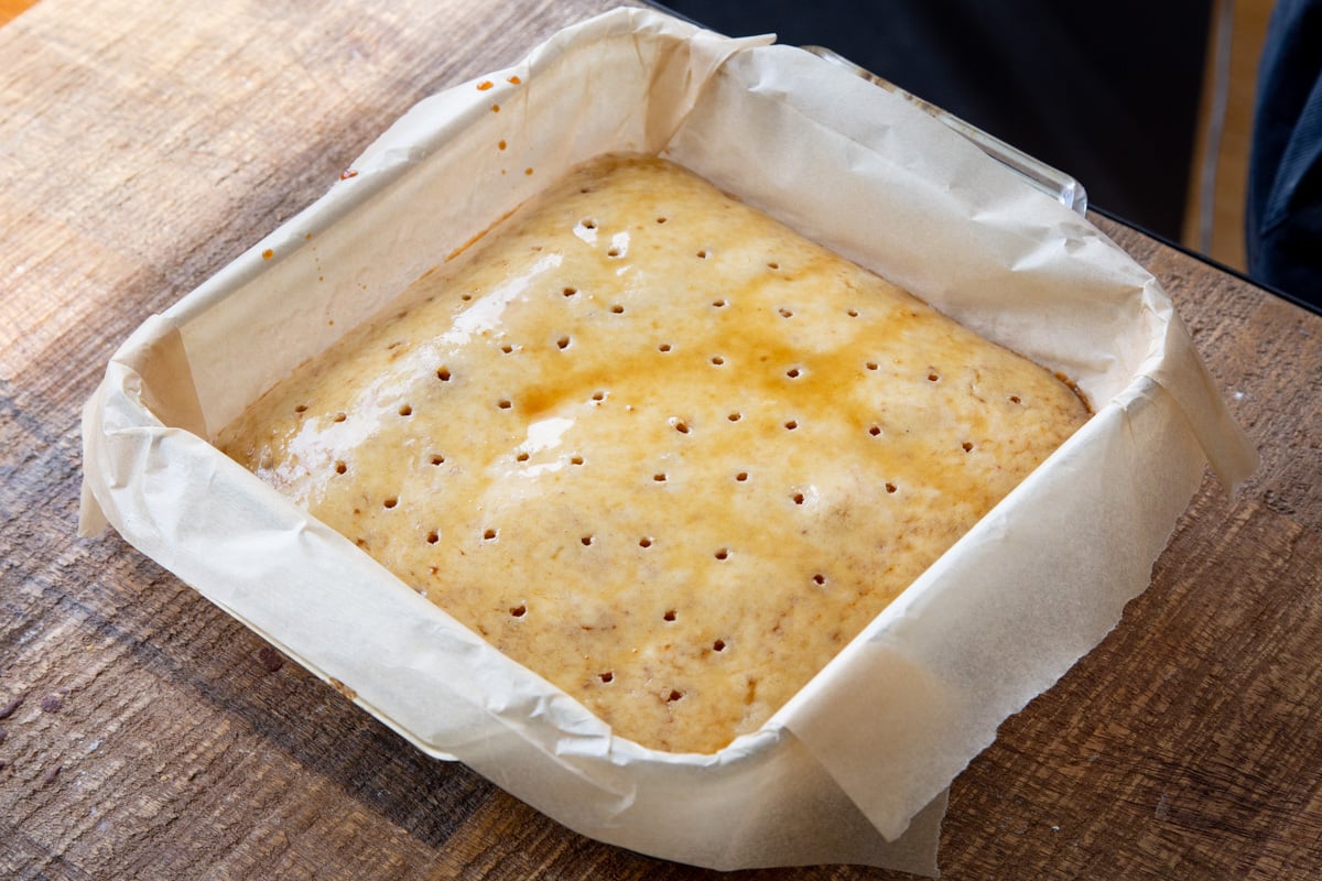 vegan sheet cake being soaked with coffee syrup to make tiramisu sheet cake