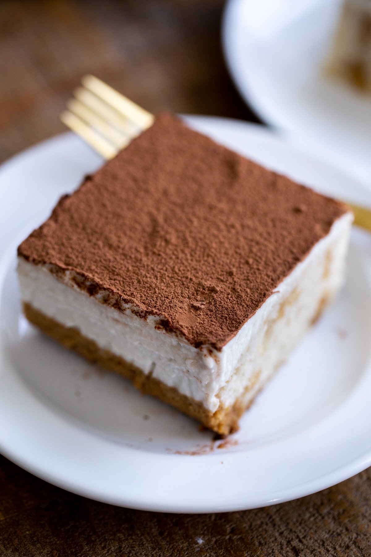 a piece of vegan tiramisu sheet cake dusted with cocoa powder served on a small cake plate