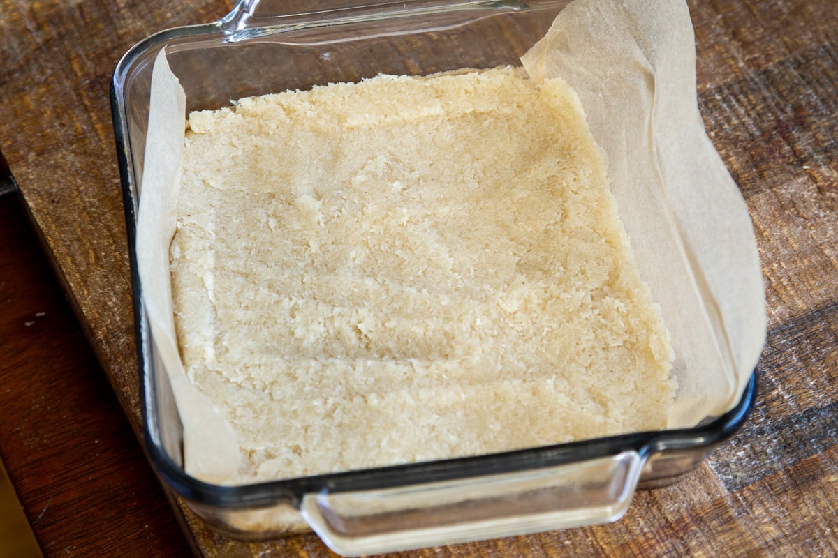 coconut burfi batter being pressed into a rectangular pan