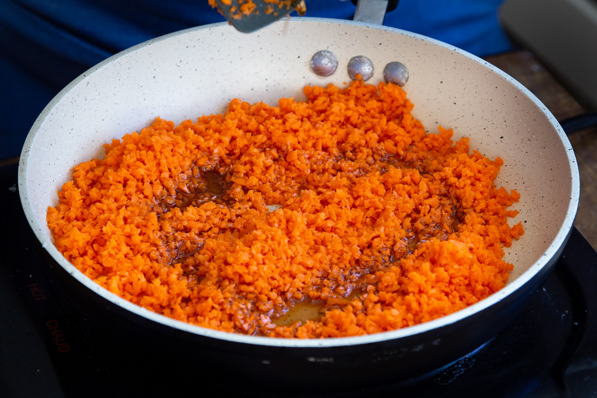 shredded carrots and maple syrup in a sauteeing pan