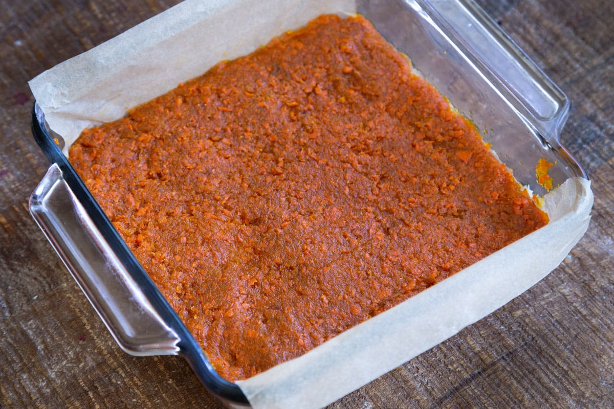 layered carrot halwa coconut burfi bars in a glass pan