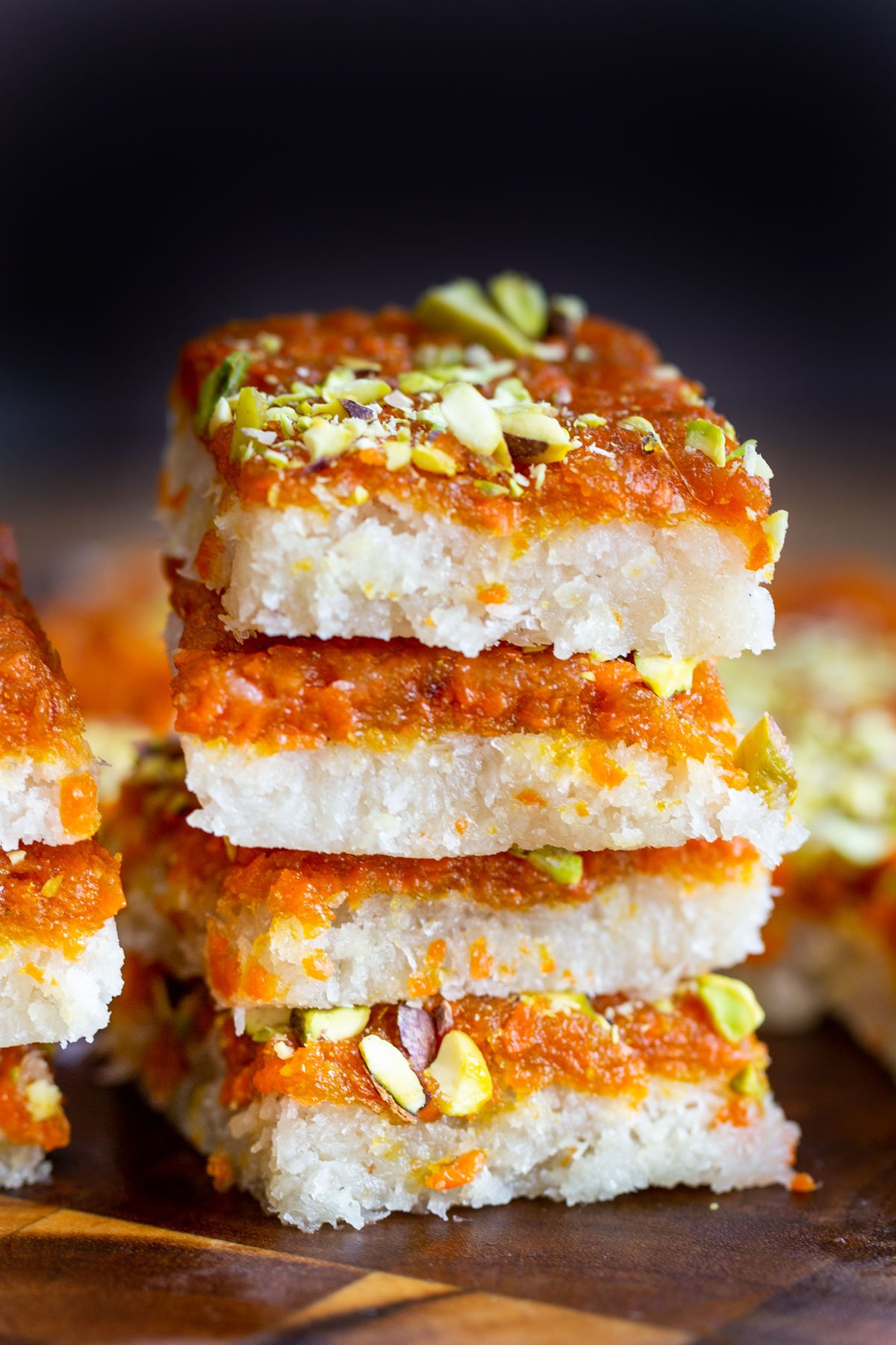a stack of carrot halwa coconut burfi bars topped with pistachios
