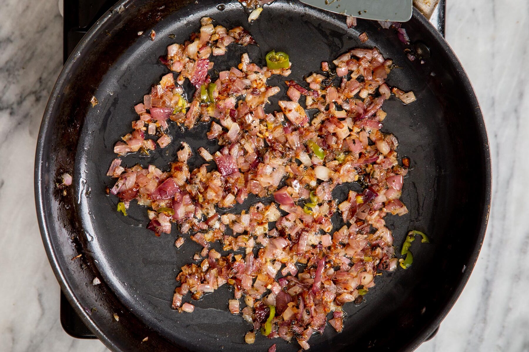 sauteed red onions and chilies in a black saucepan