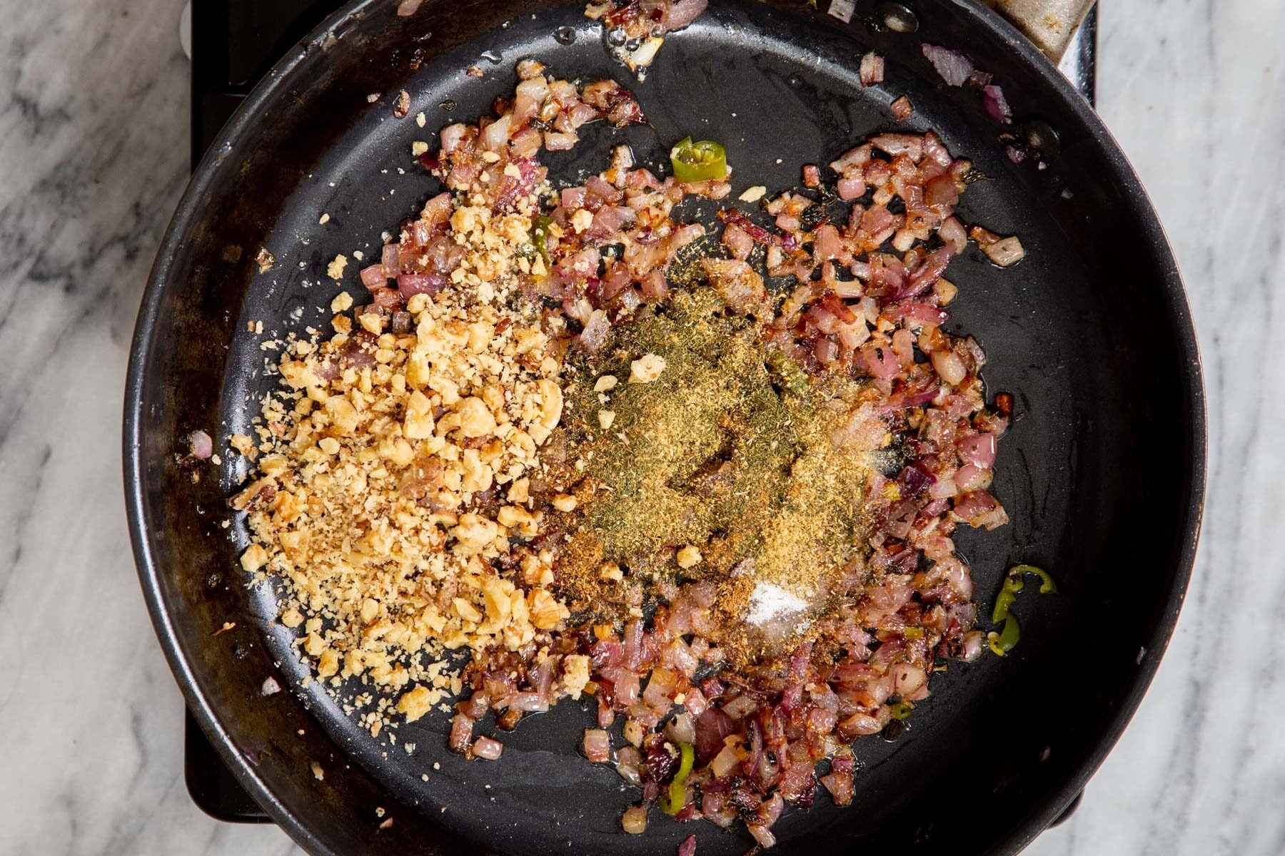 minced onions, ground spices and walnuts in a frying pan
