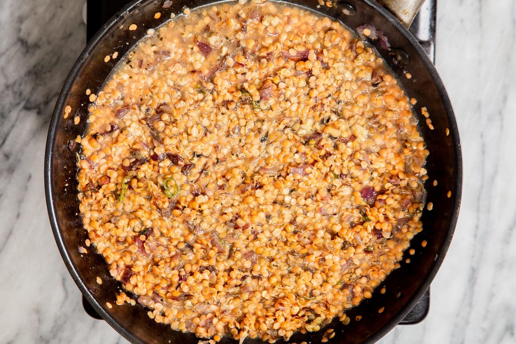 red lentils cooking in a black pan with spices