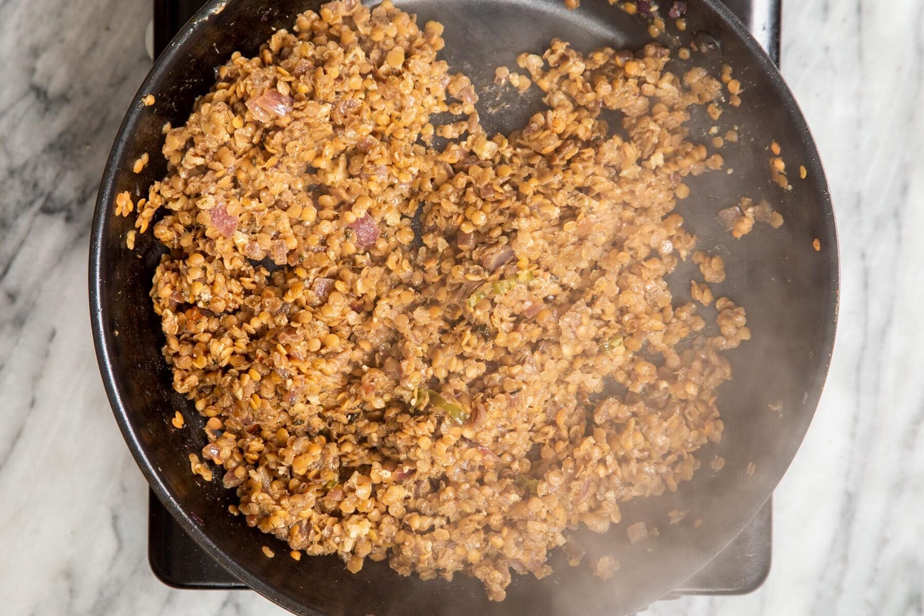 cooked lentils, onions and spices in a black skillet