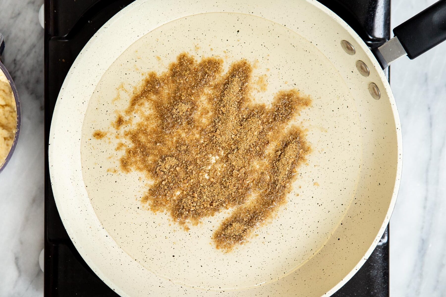 ground spices frying in a saucepan with oil