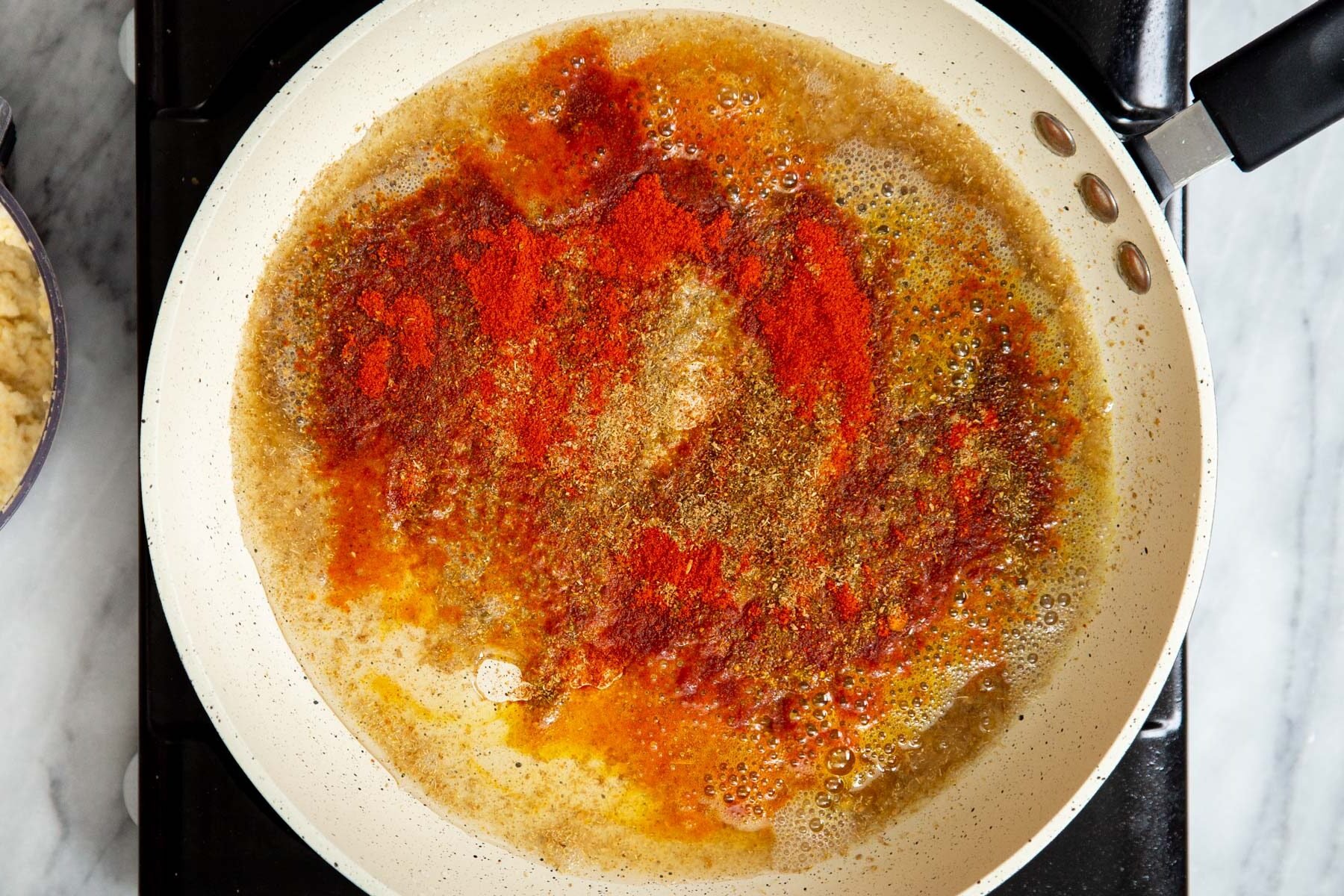 ground spices frying in a sauteeing pan